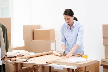 Müşterilerin siparişlerini paketlemek için ambalaj kağıdıkeserken işyerinin yanında duran online mağaza ofisi müdürü