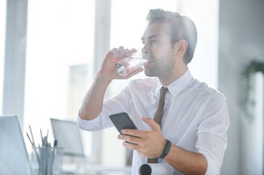 Akıllı telefon da mesaj atarken işyeri tarafından su cam sahip Genç zarif komisyoncu