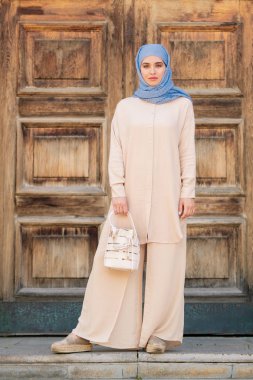 Antik şehirde ürpertici iken başörtüsü ve beyaz deri çanta tutan şık rahat takım elbise Pretty genç Müslüman kadın