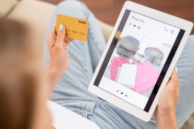 Kredi kartı ve dijital tablet ile genç shopaholic online alışverişte yeni casualwear koleksiyonu ile bakmak için gidiyor