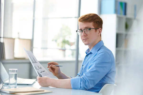 Poważny Młody Ekonomista Okularach Patrząc Ciebie Podczas Analizowania Dokumentów Finansowych — Zdjęcie stockowe