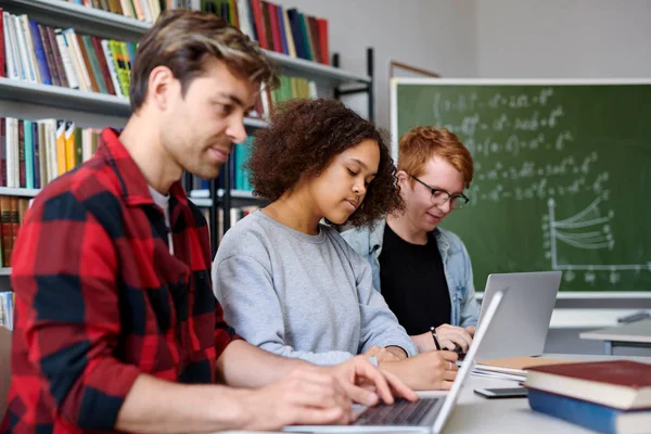 Trzech Współczesnych Studentów Pracujących Indywidualnie Podczas Lekcji Klasie Lub Bibliotece — Zdjęcie stockowe