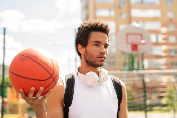 屋外トレーニング中にバスケットボールコートや遊び場に立つボールを持つ深刻なアクティブな男 — ストック写真