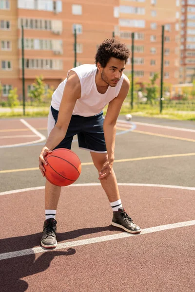 アクティブウェアの若いバスケットボール選手は プレー中にボールを投げる準備をしながら前方に曲げる — ストック写真