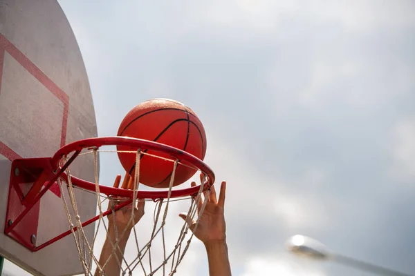 年轻篮球运动员在室外球场上比赛时将球扔进篮筐的手 — 图库照片