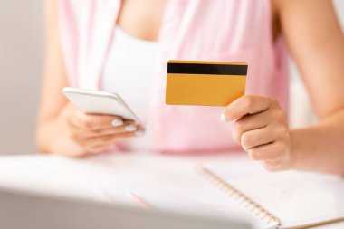 Online sipariş yapmak için promosyon arayan akıllı telefon kullanarak plastik kart ile genç kadın alışveriş eli