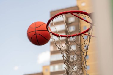 Basketbol oynamak için top arka planda gökyüzü ve ev ile sepete yakın oyuncu tarafından atılan oynamak için