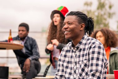 Damalı gömlekli mutlu karışık ırk lı adam ve maç yayını nı izleyen arkadaşları