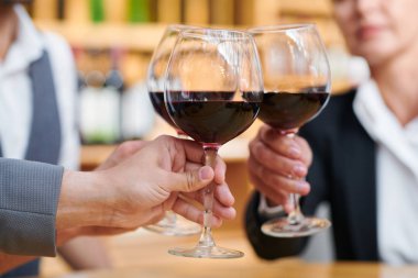 Bir grup iş adamı, bordo şarap kadehleriyle tıka lı bir şekilde başarılı bir anlaşma için birbirlerini tebrik ediyor