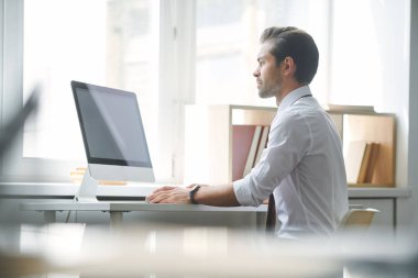 Ciddi broker bilgisayar monitörü önünde online finansal verilere bakarak konsantre