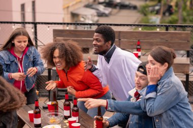 Mutlu genç çok kültürlü arkadaşlar maç yayını sırasında hokey takımı için tezahürat yaparken bira içiyor