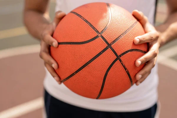 ゲーム中にバスケットに投げる前に若いアクティブな選手の手でバスケットボールをプレイするためのボール — ストック写真