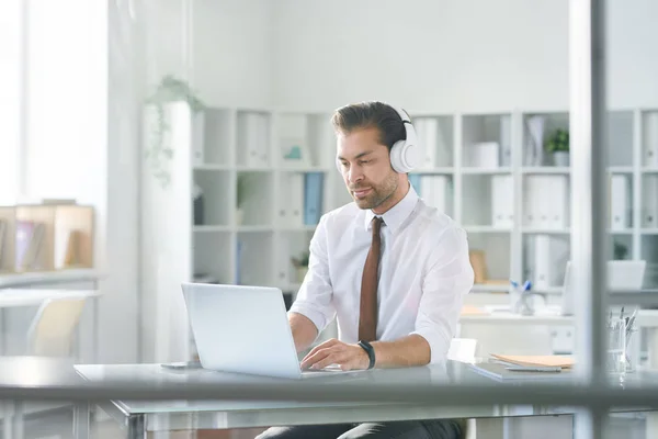 Junger Konzentrierter Geschäftsmann Tippt Kopfhörer Auf Laptop Tastatur Während Online — Stockfoto