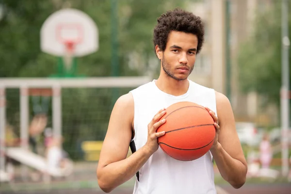 カメラの前に立ちながらバスケットボールをする若い真面目な多文化アスリート — ストック写真