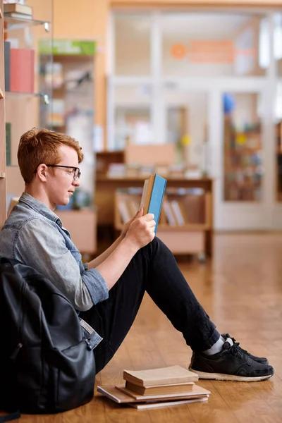 Молодий Розумний Чоловік Повсякденному Одязі Читає Книгу Сидячи Підлозі Бібліотеки — стокове фото
