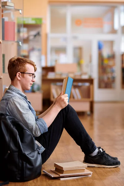 Jonge Slimme Man Casualwear Lezen Boek Terwijl Zittend Bibliotheek Vloer — Stockfoto