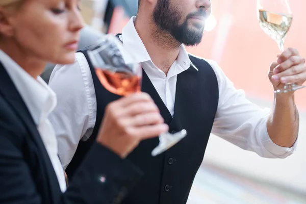胡子侍酒师与一杯白葡萄酒检查其质量和特点与同事附近 — 图库照片