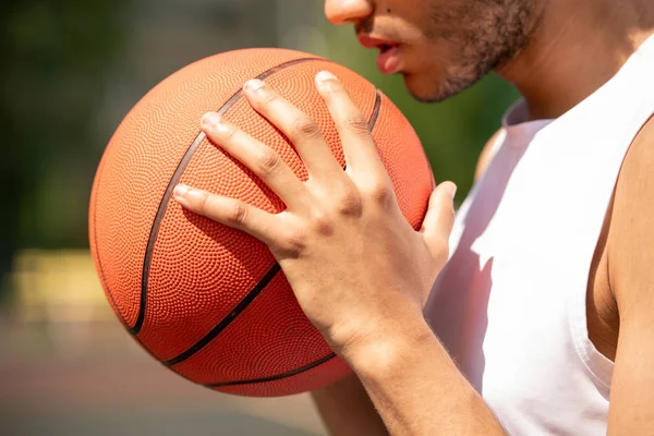 パスの準備をしながら 彼の顔と胸でボールを保持する若い現代の男子バスケットボール選手 — ストック写真