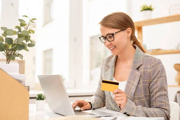 年轻的成功女商人用塑料卡看着笔记本电脑显示屏 同时搜索在线商品 — 图库照片