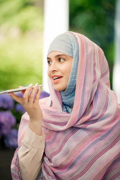 Joven Mujer Hijab Sosteniendo Teléfono Inteligente Por Boca Mientras Graba —  Fotos de Stock