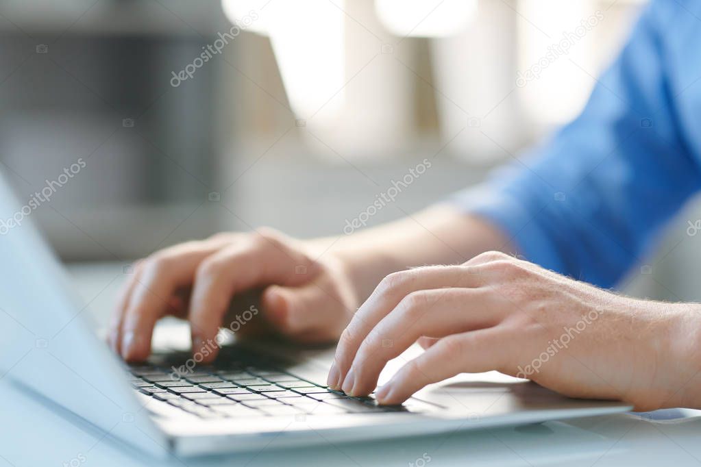 Hands of young mobile male employee pressing keys of laptop keypad while working over new project