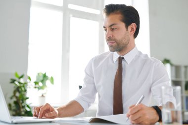 Genç ciddi analist veya finans uzmanı dizüstü bilgisayar ekranında online verilere bakıyor