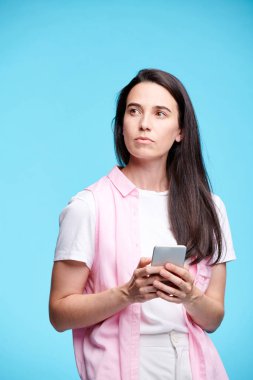 Yalnız akıllı telefon kaydırma sırasında kenara bakarak casualwear genç ciddi esmer kadın