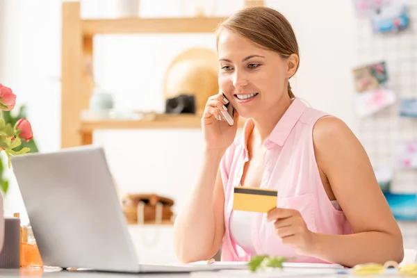 ネットで注文しながらオンラインショップのコンサルタントにクレジットカードの数を伝えるスマホを持つ可愛い女性 — ストック写真