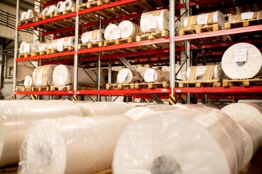 Depolama fabrikası raflarında polietilen membran yeni üretilen büyük bobinler haddelenmiş ve paketlenmiş Satırlar