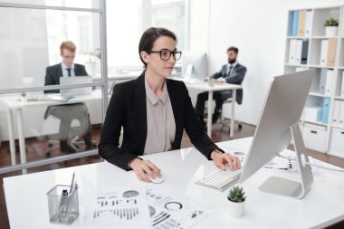 Ofiste, muhasebeci veya yönetici kavramı masada oturan Pc kullanarak gözlük takan genç iş kadını portresi
