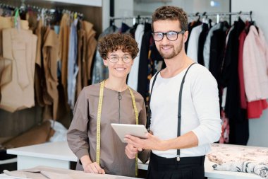 İki genç başarılı yaratıcı tasarımcılar kamera önünde atölye ayakta ve yeni koleksiyon üzerinde çalışıyor