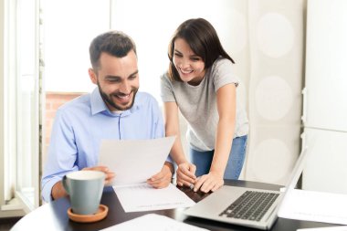 Rahat mutfakta gelir vergisi beyannamesi verirken kağıtları inceleyen içerik genç çift