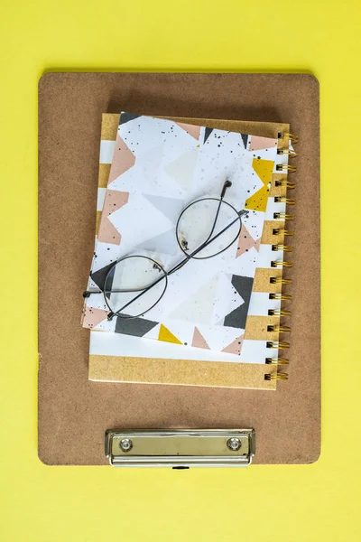 Defteri Dizüstü Bilgisayar Pano Üzerindeki Gözlükler Sarı Arka Plan Üzerinde — Stok fotoğraf