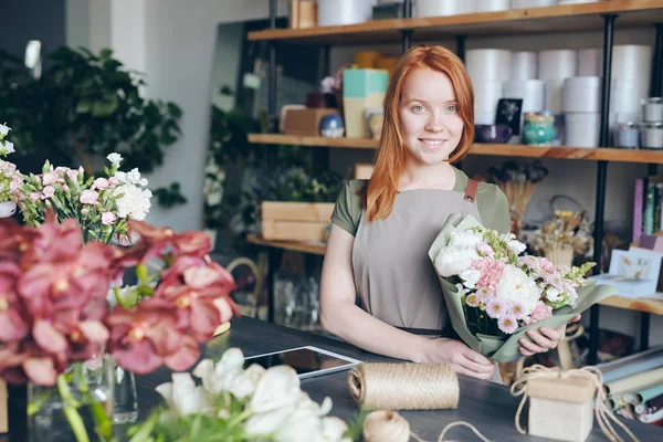 Feliz Atractiva Pelirroja Florista Joven Delantal Sosteniendo Hermoso Ramo Mirando — Foto de Stock