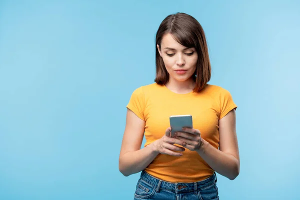 Mulher Séria Muito Jovem Rolando Smartphone Enquanto Olha Através Novas — Fotografia de Stock