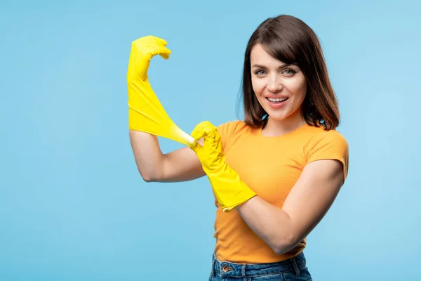 Szczęśliwa Młoda Gospodyni Żółtym Shirt Zakładanie Rękawic Gumowych Ręce Przed — Zdjęcie stockowe