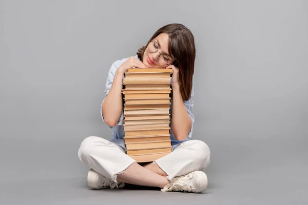 聪明的女性学生或图书管理员交叉腿保持她的头在书的顶部 而梦想阅读他们所有 — 图库照片