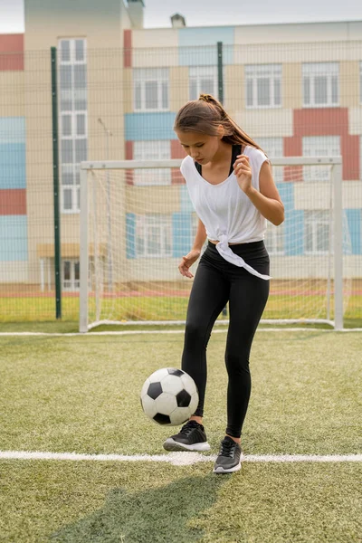 환경에서 훈련하는 축구공을 차면서 스포츠 필드에 서있는 스포츠웨어에 소녀를 — 스톡 사진