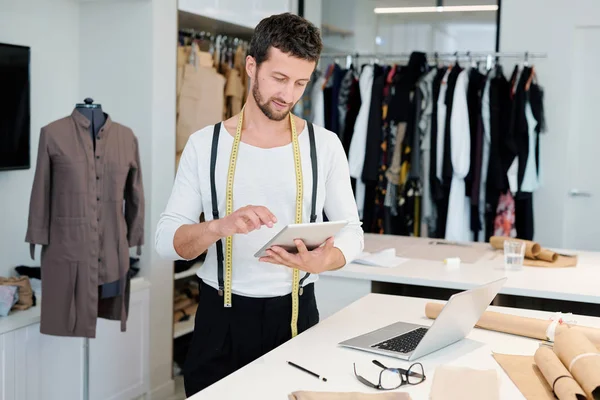 Touchpad'de gezinirken ve yeni moda trendlerini araştırırken ağ üzerinde yoğunlaşan genç adam