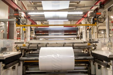 Fabrika atölyesinde büyük haddelenmiş yeni üretilen şeffaf polietilen film ile büyük endüstriyel makine