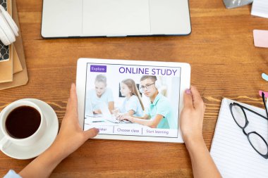 Ekranda eğitim web sitesinin ana sayfası ile dokunmatik yüzey tutan genç kadın ellerin üst görünümü