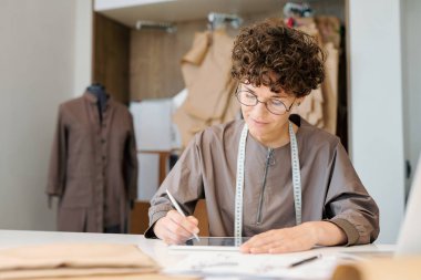 Genç kadın tasarımcı yeni moda koleksiyonu için olsa dijital modeller bakarak konsantre