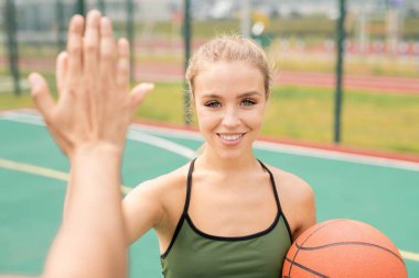 Aktif giyimpretty genç sarışın kadın oyun alanında basketbol oyunu önce arkadaşına yüksek beş veren