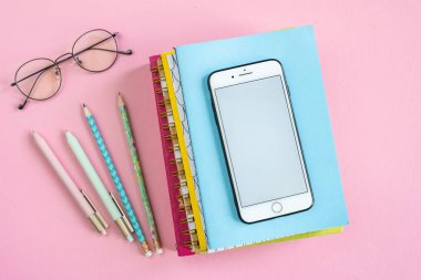 Business objects for planning work, smartphone and eyeglasses of manager on pink table or background