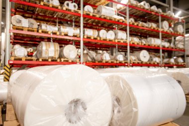 Racks of rolled and packed polyethylene film in storage area of large contemporary chemical production factory clipart