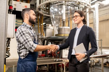 İki genç iş ortağı ortaklık ve üretim değişimi sözleşmesini imzaladıktan sonra el sıkışırken