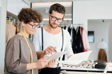 Pretty genç kadın terzi ve onun meslektaşı mevsimlik moda koleksiyonu için yeni fikirler tartışıyor