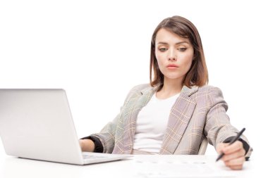 Dizüstü bilgisayar önünde otururken formalwear çalışma notları yapma pensive genç kadın