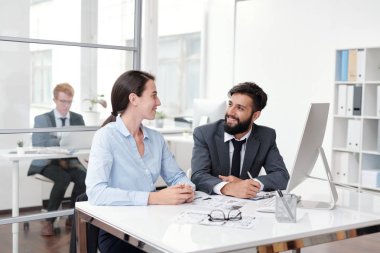 Ofiste masada otururken birbirine bakan ve gülümseyen iki meslektaşının portresi, kopya alanı