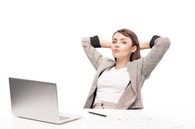 Dizüstü bilgisayarın önünde mola verirken size bakan formalwear genç ciddi veya dinlendirici kadın çalışan